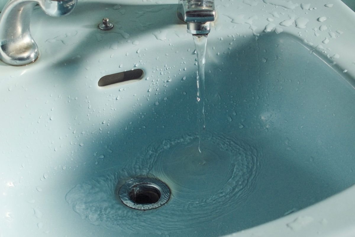 A plumber inspecting the waste pipe under a kitchen sink